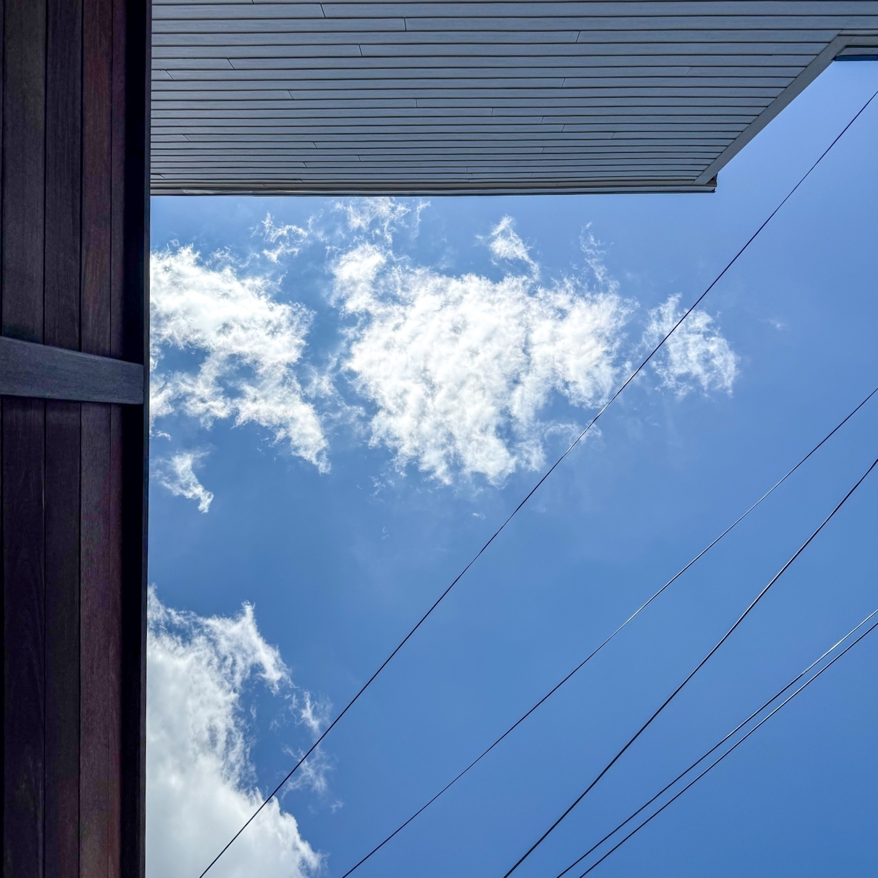 Photo taken laying down in the backyard at my co-working space of a blue sky with some clouds.
