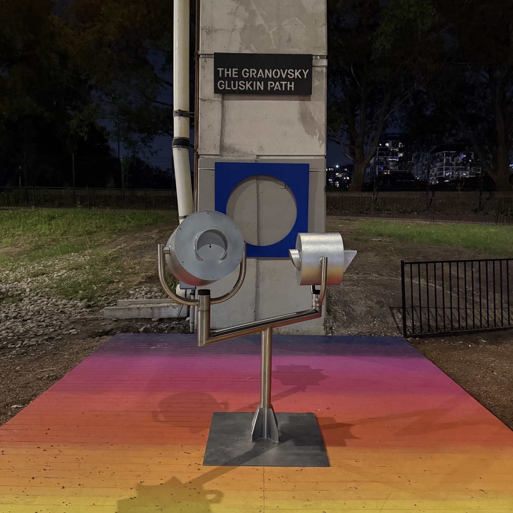 Two thermal cameras are mounted on a colourful platform beneath a sign that reads The Granovsky Gluskin Path against a nighttime cityscape.