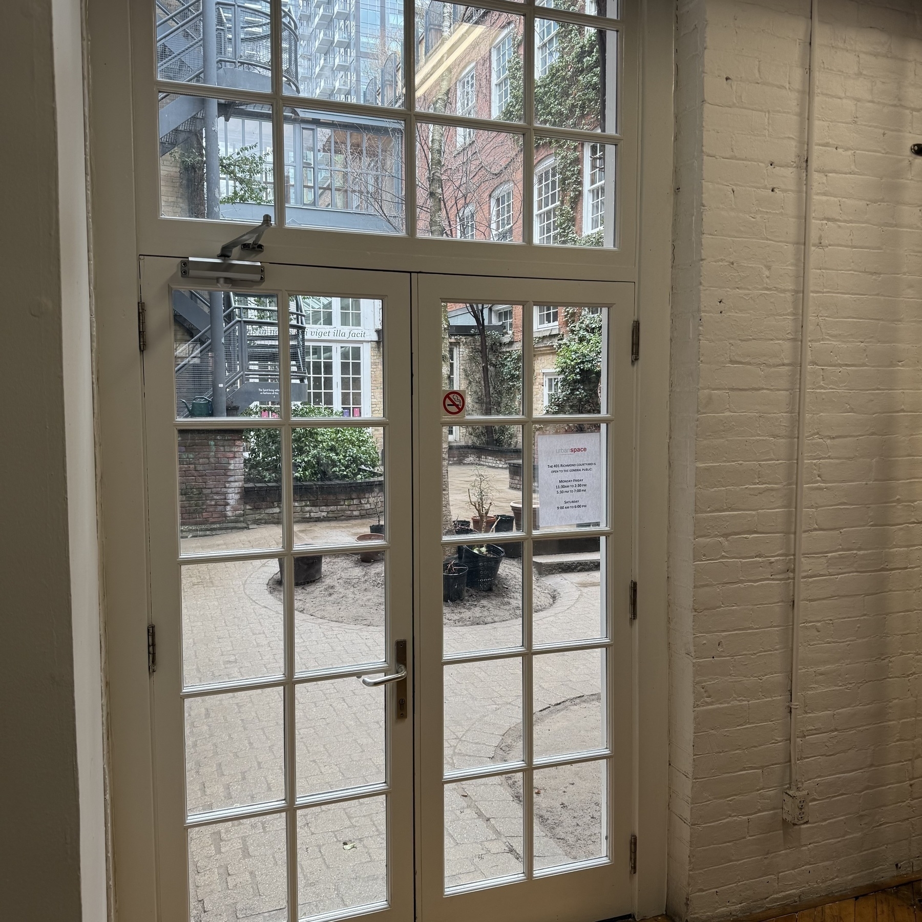 A photograph taken of the courtyard of 401 Richmond, captured through glassed French doors. 